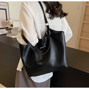 Detail of black pebbled leather tote bag with silver bar accent on shoulder strap