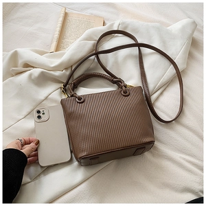 Detailed view of brown pleated bucket bag with a phone to show its compact mini size