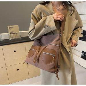 Detail of tan canvas backpack with heart-shaped leather pockets and silver zippers