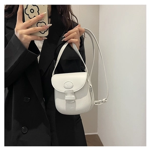 Detail view of a white textured leather crossbody bag shown in a mirror selfie styling