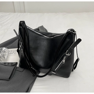 Detail of matte black tote bag showing silver zippers and wide adjustable shoulder strap