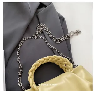 Close-up of a pale yellow ruched handbag showing metallic silver chain strap details