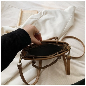 Detail of the brown pleated bucket bag showing the woven handle and spacious inner lining