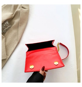 Top view of red glossy leather shoulder bag interior with magnetic closure and gold chain