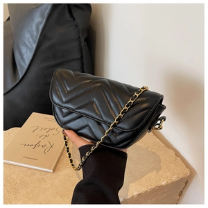 Close-up of black quilted leather bag with V-shaped chevron stitching and gold chain strap