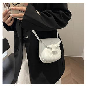 Detail of white cross-body phone bag with vertical embossing texture worn by a model