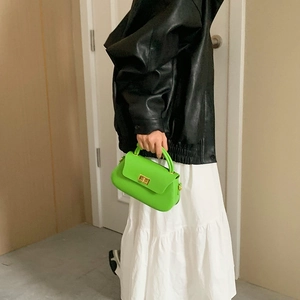 Vibrant green leather handbag with gold square buckle and chain strap shown on model