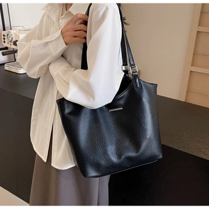 Detail shot of the black lychee pattern leather tote bag with silver metal bar accents