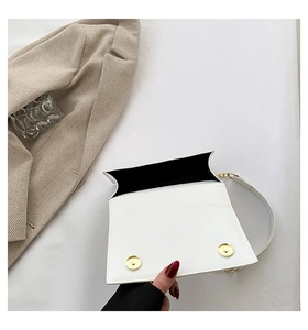 Detail of white leather crossbody bag with dual magnetic buckles and chain strap