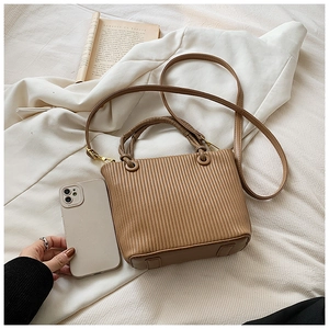 Detailed view of vertical pleated texture on brown bucket bag with gold hardware buckle