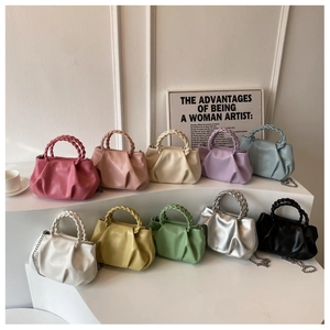 Detail view of colorful pleated crossbody bags with woven handles and metal chains