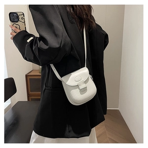 Detail of white crossbody flap bag with vertical embossed texture and oval metal logo plate