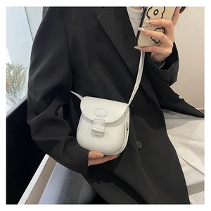Close-up of a white textured PU leather saddle bag worn by a model in a black blazer