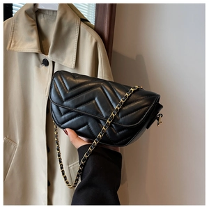 Detail of black chevron quilted leather crossbody bag with elegant gold chain strap