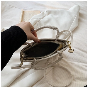 Internal view of cream pleated bucket bag showing metal zipper and woven handle detail
