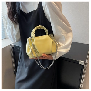 Close-up of a pale yellow pleated cloud bag with woven handle and silver chain strap