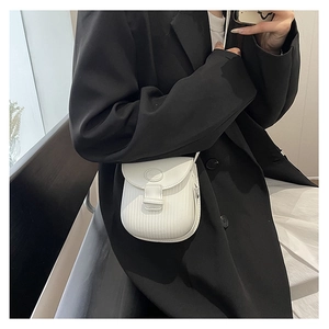 Detailed macro view of white mini crossbody bag featuring vertical stripe embossed texture