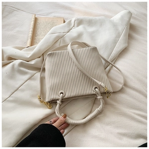 Detail of white pleated bucket bag with vertical texture and gold metal buckle hardware