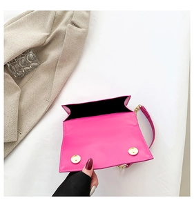 Detail view of pink leather handbag with magnetic gold closures and black lining