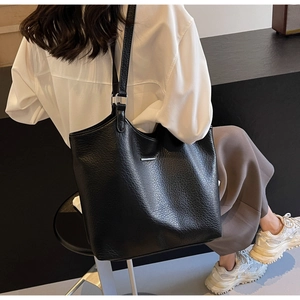 Detail of minimalist black pebbled leather tote bag with elegant silver metal fastener