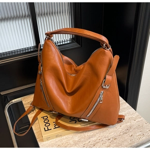 Detailed close-up showing the soft synthetic leather texture and metal zippers of the bag