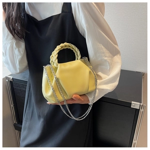 Detail view of lime yellow pleated cloud bag with woven handle and silver chain strap