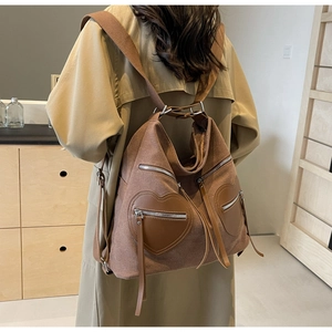 Detail view of a large brown corduroy backpack with leather heart-shaped pockets on the back