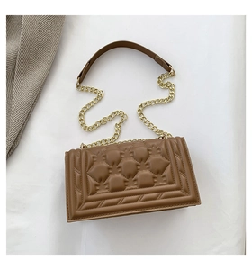 Detail of brown quilted shoulder bag with geometric embossing and gold chain strap