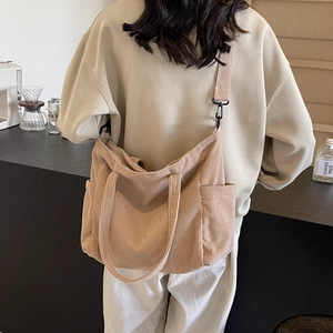 Minimalist beige corduroy tote bag with adjustable strap worn in a casual lifestyle setting