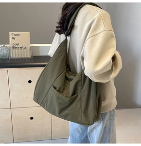Detailed view of the olive green nylon tote bag featuring a wide shoulder strap and pocket