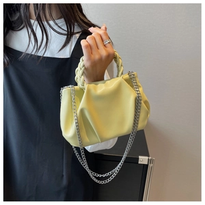 Detail showing soft yellow ruched cloud bag with woven handle and silver chain strap