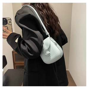 Detail of mint green crossbody bag with unique pleated texture and metal buckle closure
