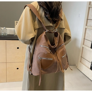 Close-up of a brown corduroy backpack featuring two distinct heart-shaped leather pockets