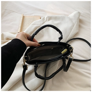 Detail view of the black pleated bucket bag with woven handle and spacious interior storage