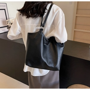 Detail showing the black lychee texture leather tote bag with silver metal buckle on strap