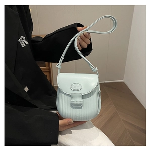 Detail of light blue PU leather crossbody bag featuring vertical stripe texture and logo