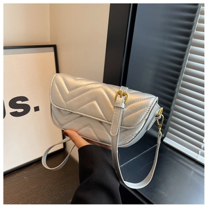 Close-up of silver V-quilted texture and gold metal buckle on a modern small square bag