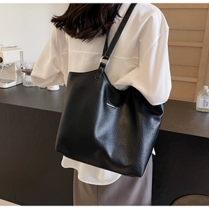 Close-up of black pebbled leather tote bag with silver metal buckle on shoulder strap