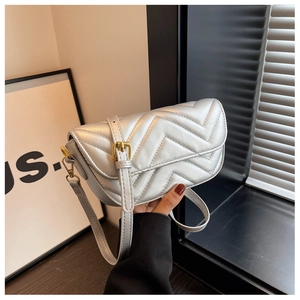 Close-up of silver quilted leather shoulder bag featuring V-shaped texture and gold hardware