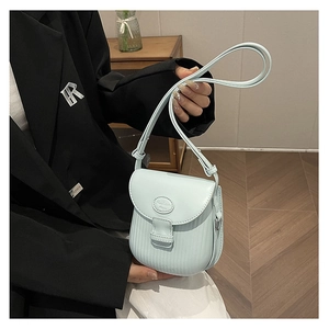 Detail of light blue textured crossbody bag with fashion logo and vertical stripe pattern
