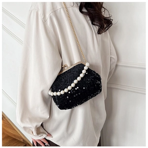 Detail of a black sequin shell evening bag with pearl handle and golden metal chain strap