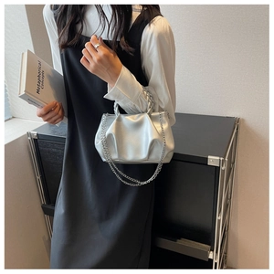 Detail of silver pleated small square bag with woven handle and metallic chain strap
