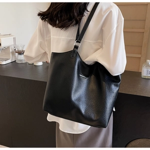 Detailed macro view of black leather tote bag featuring high-quality lychee texture grain