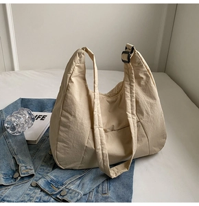 Close-up of beige nylon tote bag with black plastic strap buckle on denim fabric