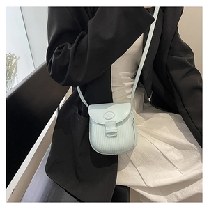 Close-up of light blue pleated leather crossbody bag worn by model in minimalist setting