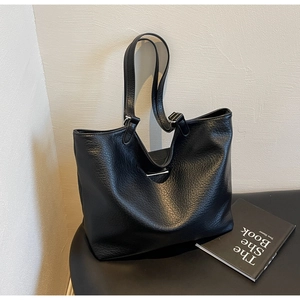 Close-up of black pebble grain leather texture and durable straps on a large tote bag
