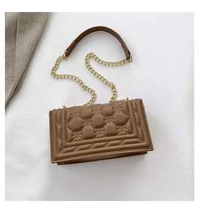 Detailed macro view of brown synthetic leather with 3D geometric quilted pattern and chain