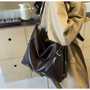 Detailed close-up of dark brown tote bag with silver zippers and faux leather texture
