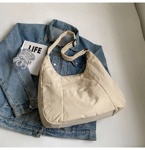 Detailed close-up of beige nylon crescent bag texture with wide adjustable strap