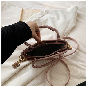 Detail of dusty pink pleated bucket bag showing the inner zipper pocket and woven handle